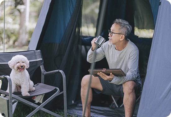 a man sitting in his tent with a cup in his hand
