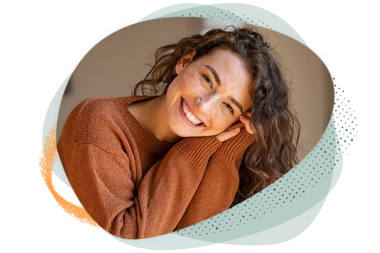 Woman with orange sweater on, smiling at the camera