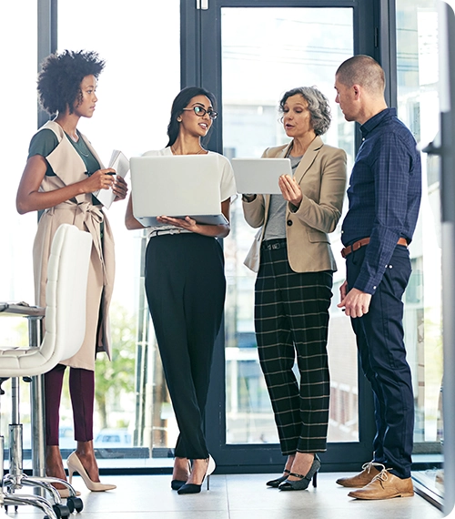 A group of office employee standing and talking with laptops on their hands