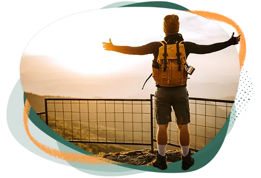 Hombre practicando senderismo de pie en un mirador con los brazos extendidos