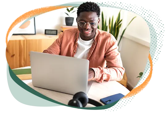 Male sitting at a table and smiling at his laptop
